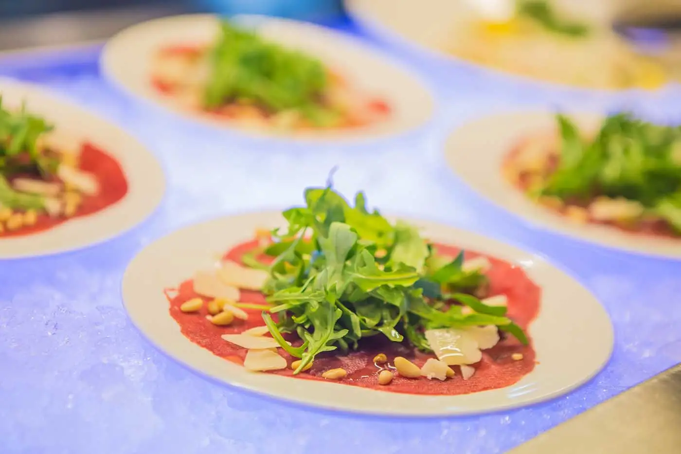 Borden carpaccio met rucola en pijnboompitten op het verlichte buffet
